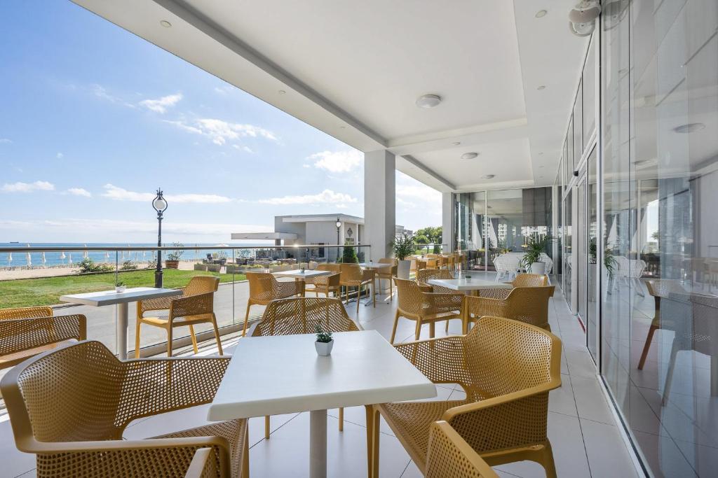 Moderns terases dizains ar skatu uz jūru, kas piedāvā ērtas dzeltenas krēsla un galdu kombinācijas, ideāla vieta relaksācijai.