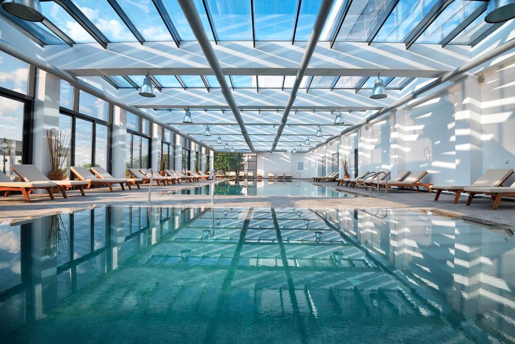 Lielisks iekštelpu peldbaseins ar modernu arhitektūru, bagātīgu dabisko apgaismojumu un ērtām atpūtas vietām gar malām. Ideāla vieta relaksācijai un atpūtai.
