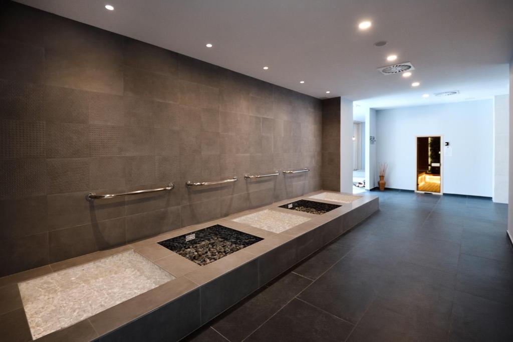 Mūsdienīgs spa telpas interjers ar akmens flīzēm, relaksācijas zonu un hromētām rokturiem. Izteiksmīgas krāsas un elegants dizains rada mierīgu atmosfēru.