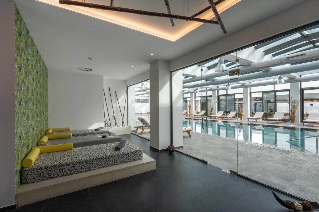 Mūsdienīgs spa atpūtas zona ar dīvāniem un skatu uz baseinu. Zaļā fona siena piešķir telpai relaksējošu atmosfēru.