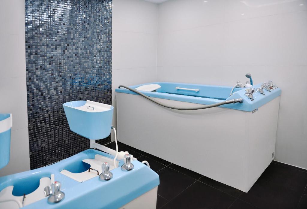 Mūsdienīga un stilīga vannas istaba ar zilu un baltu aprīkojumu, kas ietver vannu un kāju vanniņu, kā arī elegantu flīžu apdari. Ideāla vieta relaksācijai un atjaunošanai.