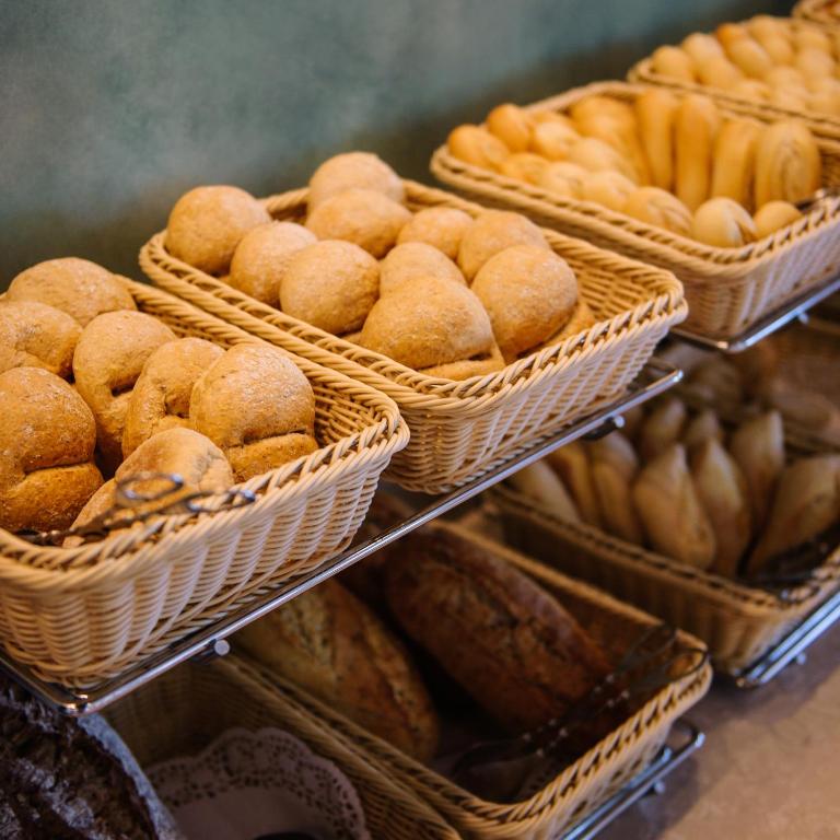 Maizes grozi ar dažādiem maizes izstrādājumiem, tostarp apaļām maizītēm un garajām maizēm, izvietoti uz plauktiņiem.