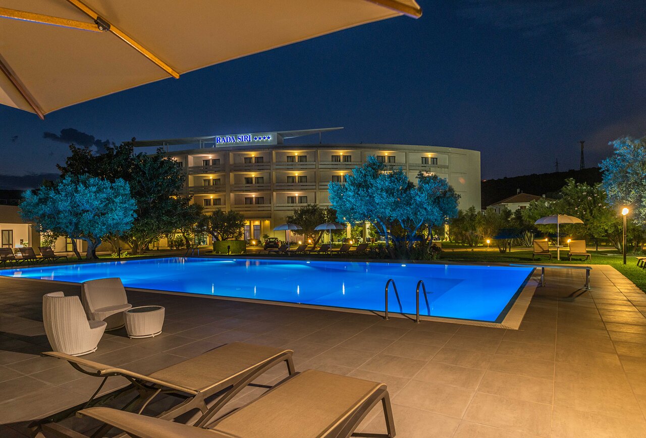 Rada Siri Hotel baseins naktī ar apgaismotu vidi.