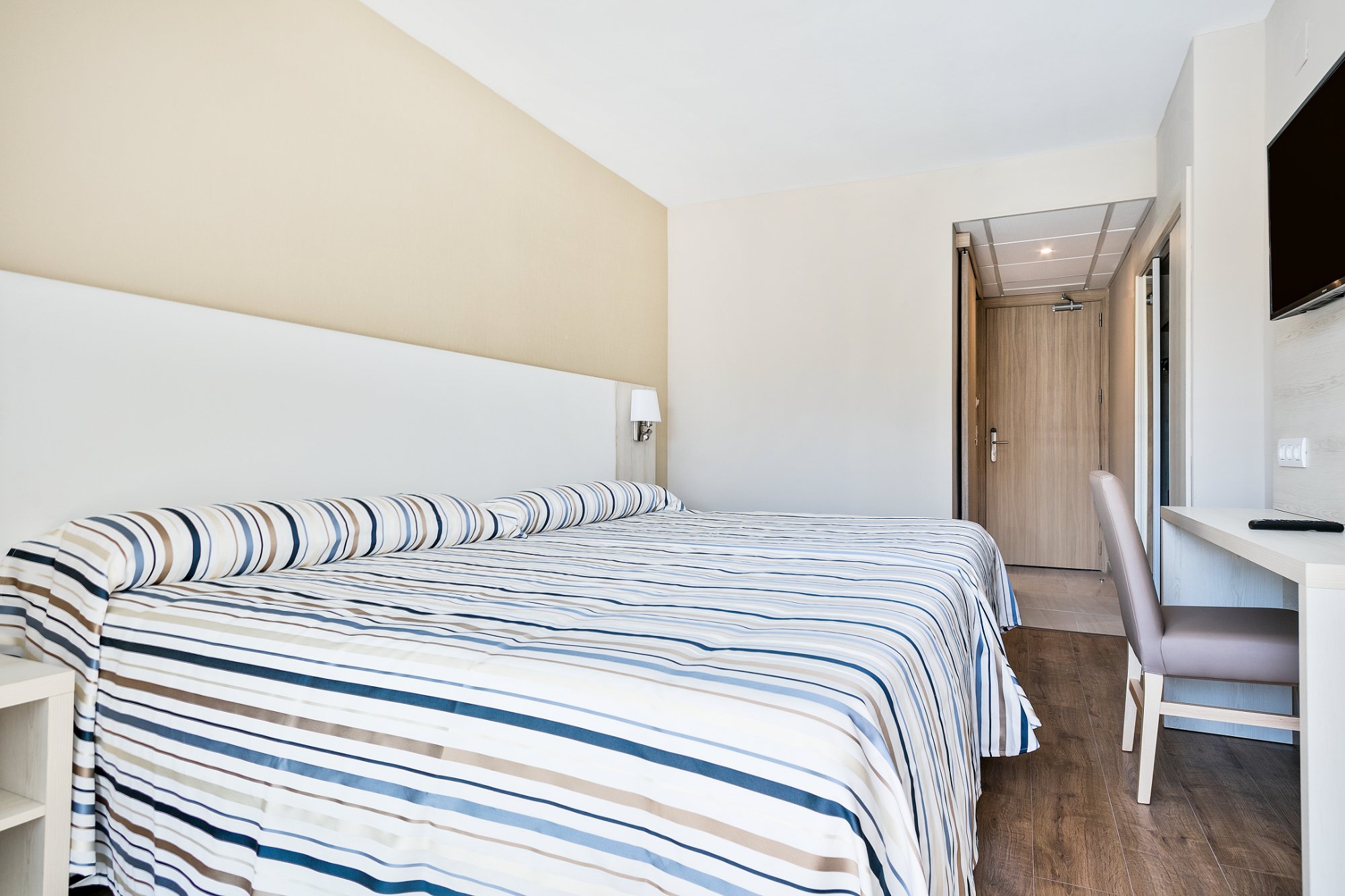 Gaišs Best San Diego viesnīcas numurs ar ērtu gultu un darba galdu.