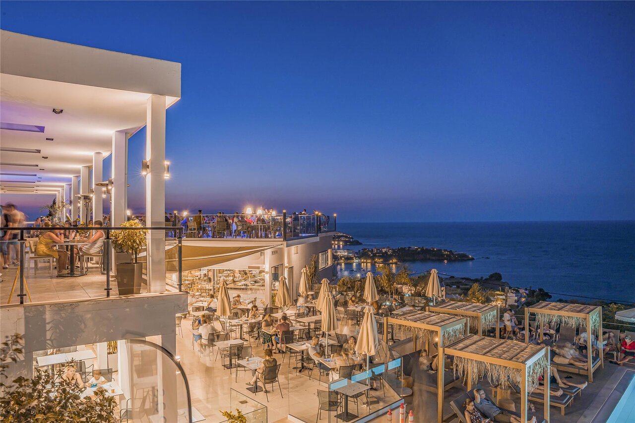 Panorama Village Hotel vakara terase ar elpu aizraujošu skatu uz jūras piekrasti.