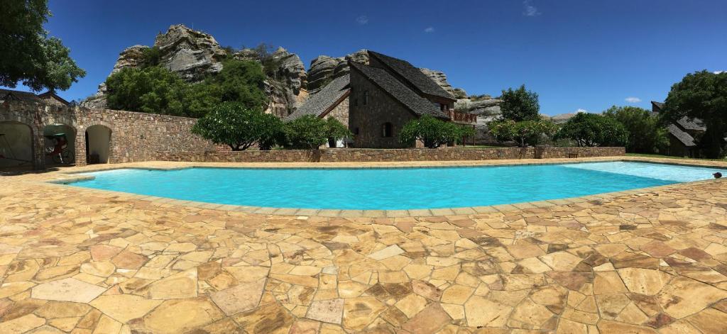 Peldbaseins pie viesnīcas Jardin du Roy ar akmens apdari un kalnu fonu.