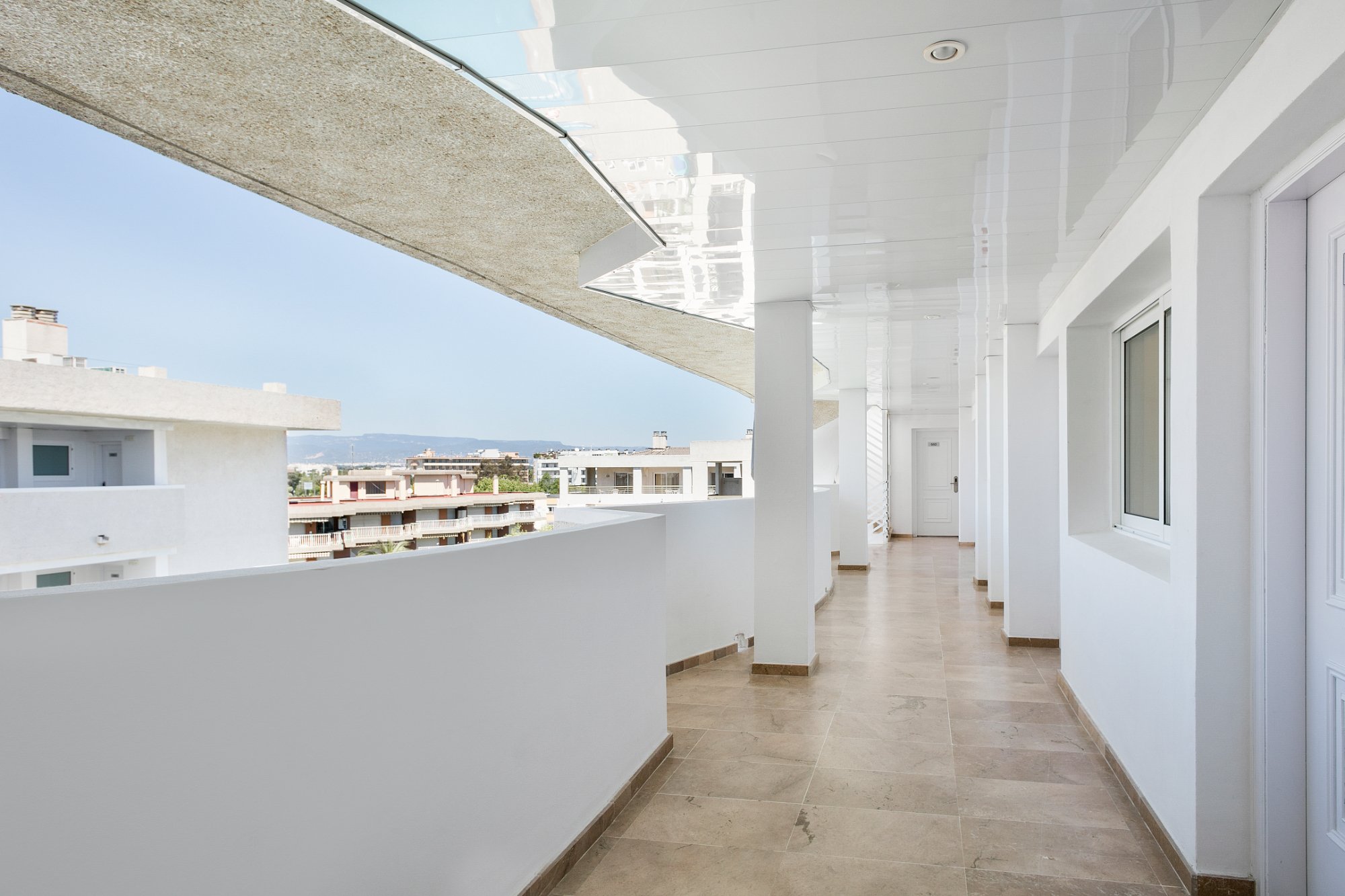 Gaišs Best Da Vinci viesnīcas āra gaitenis ar flīžu grīdu un skatu uz pilsētu saulainā dienā.