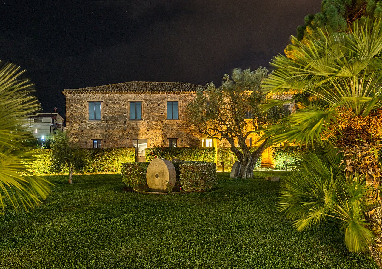 Rada Siri Hotel dārzs ar apgaismotu ēku naktī