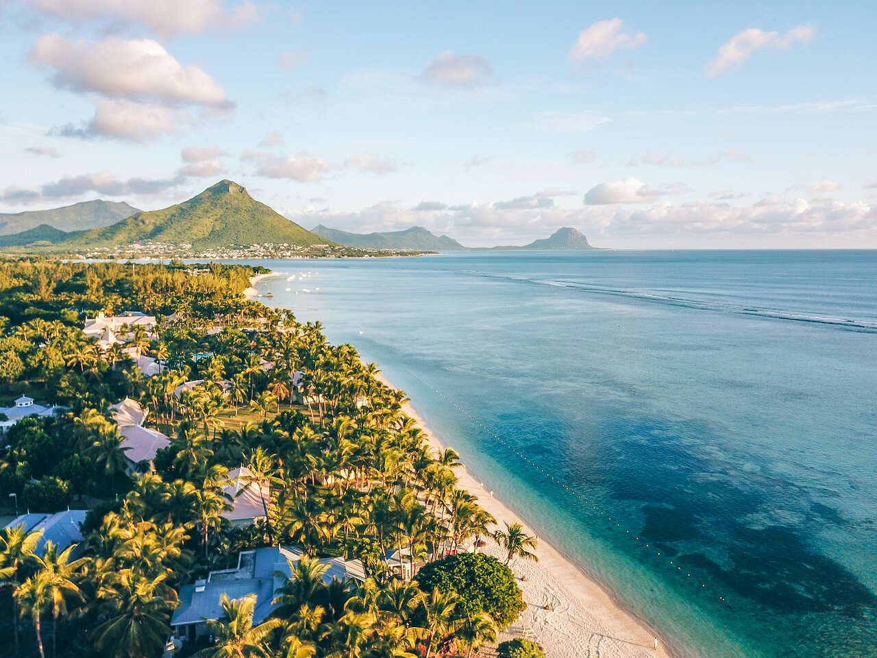 Tropisks pludmales skats ar palmām, mierīgu jūru un kalniem fona. Ideāli piemērots ceļojumu vai atpūtas tēmai. panoramic view with beach and pools