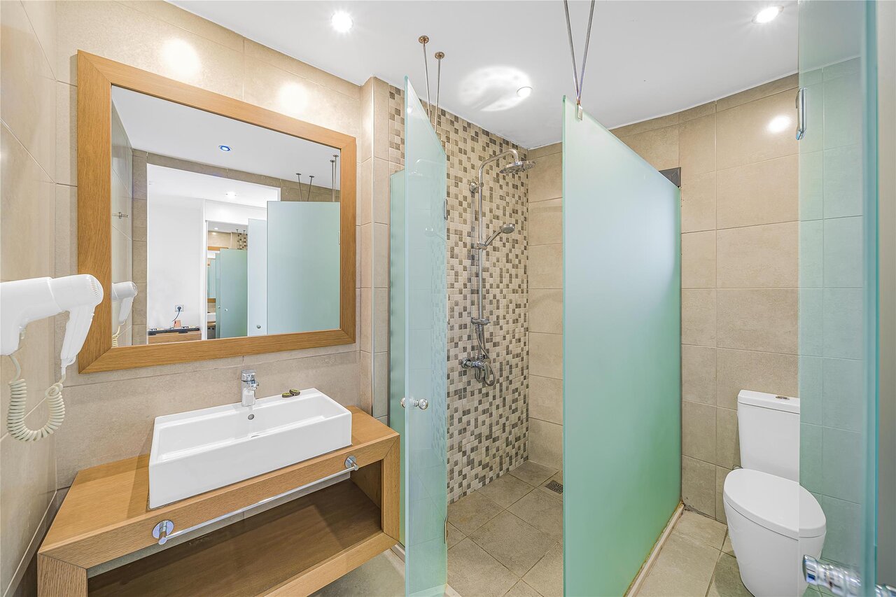 Panorama Village Hotel numura vannas istaba ar dušas kabīni un koka apdari.