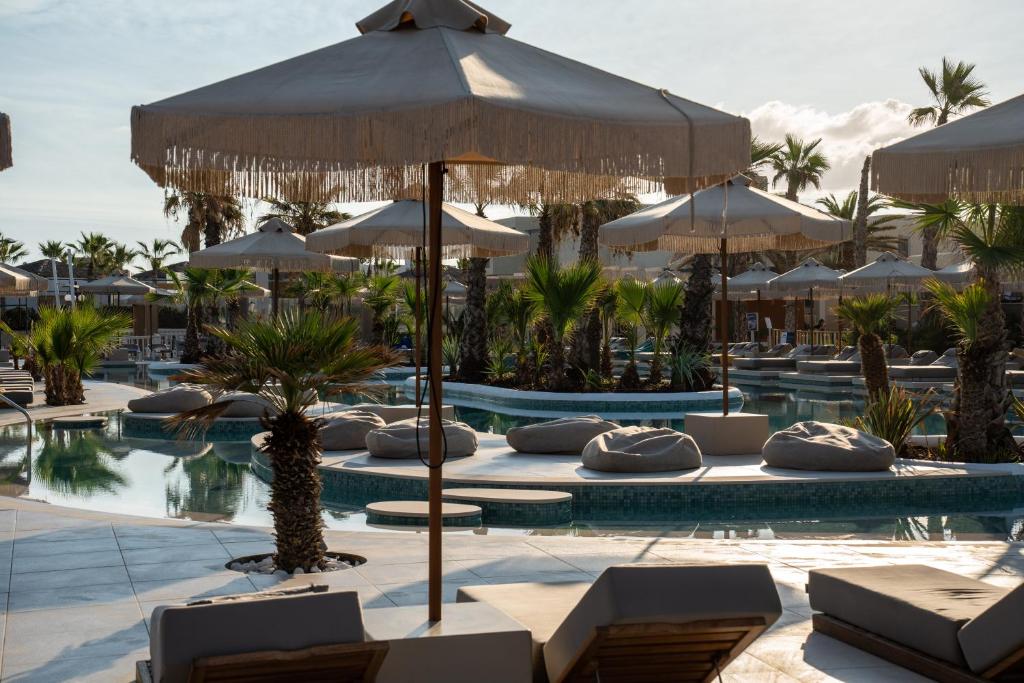 Peldbaseins ar saules lietussargiem un palmām, radot relaksējošu atmosfēru pludmales atpūtai. Ideāla vieta, lai izbaudītu sauli un mieru.
