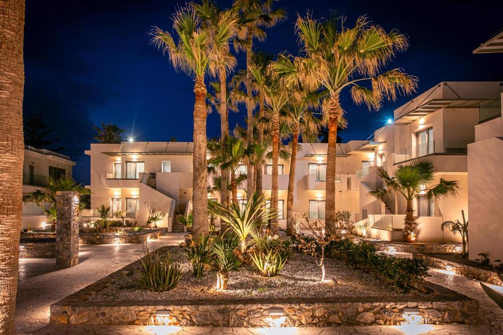 Viesnīca Saint George Gournes Bay piekrastē, apgaismota dārzā naktī.