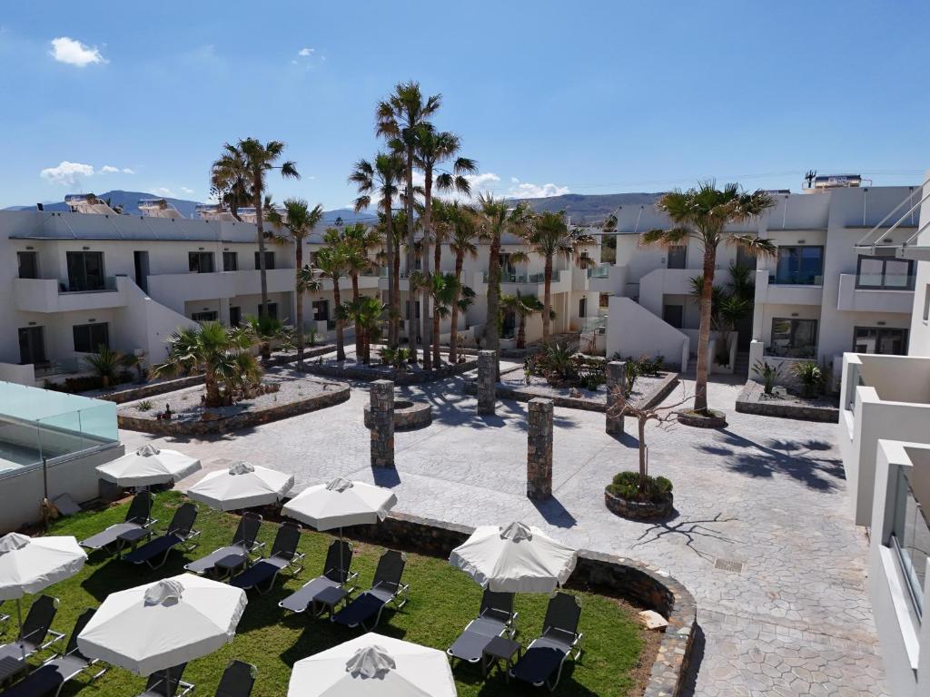 Skats uz viesnīcu Saint George Gournes Bay ar palmām un sauļošanās krēsliem.