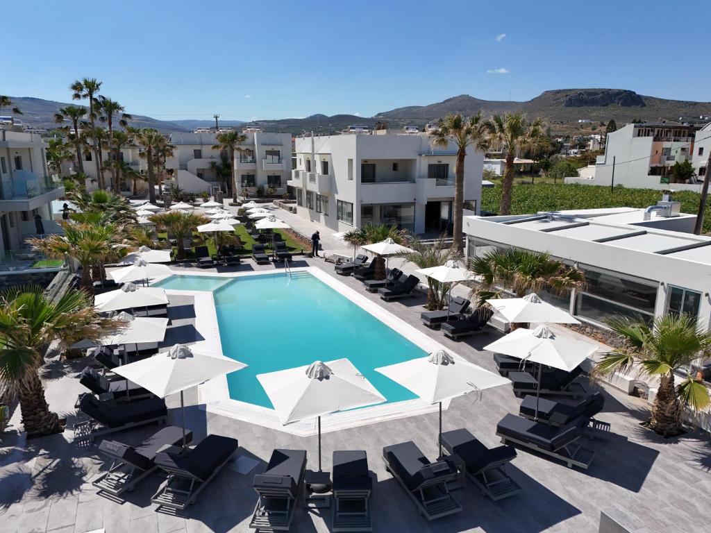 Viesnīcas Saint George Gournes Bay baseins ar sauļošanās krēsliem un palmu kokiem.