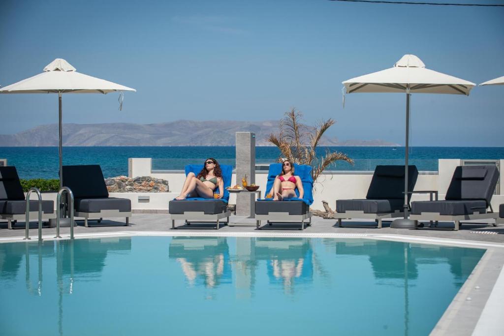 Divas sievietes atpūšas pie baseina viesnīcā Saint George Gournes Bay.