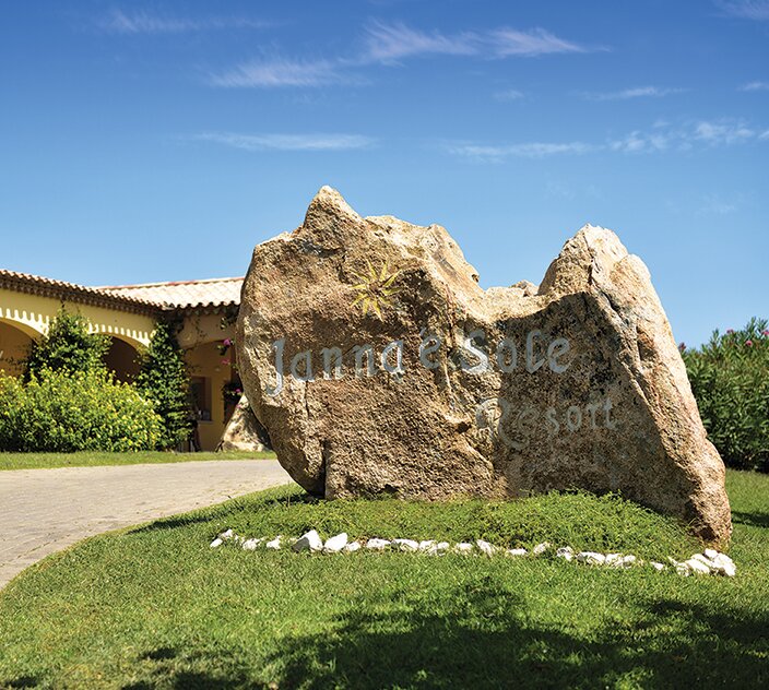 Janna 'e Sole Resort akmens zīme un ieeja saulainā dienā.