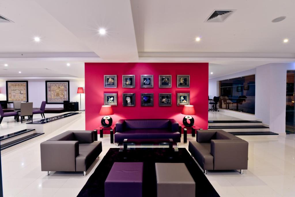 Mūsdienīga viesnīcas viesistaba ar rozā sienu un mākslas darbiem, Vila Gale Atlantico
