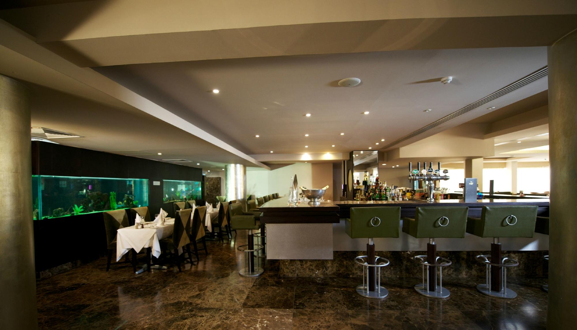 Adams Beach viesnīcas restorāns ar akvāriju un bāra letes skatu.