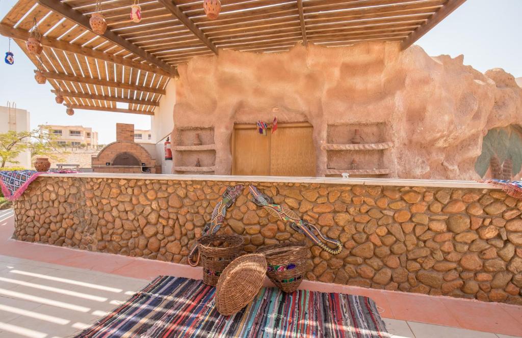 Atpūta piekraste pie Long Beach Resort Hurgada ar akmens sienu un tradicionālo krāsaino paklāju.