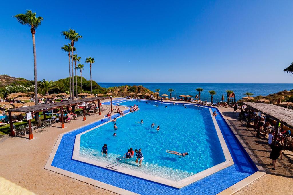 Auramar Beach Resort baseins piekrastē ar viesiem, saulains laiks.