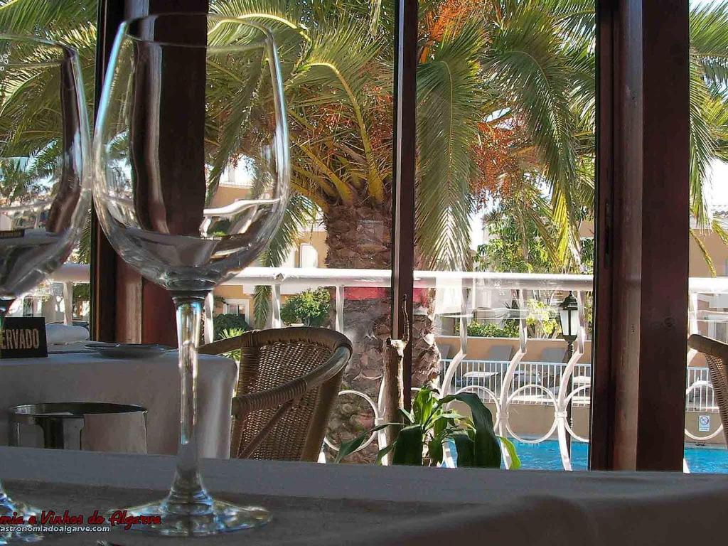 Skats uz baseinu no restorāna Pestana Palm Gardens Ocean & Golf Villas, ar glāzēm uz galda.