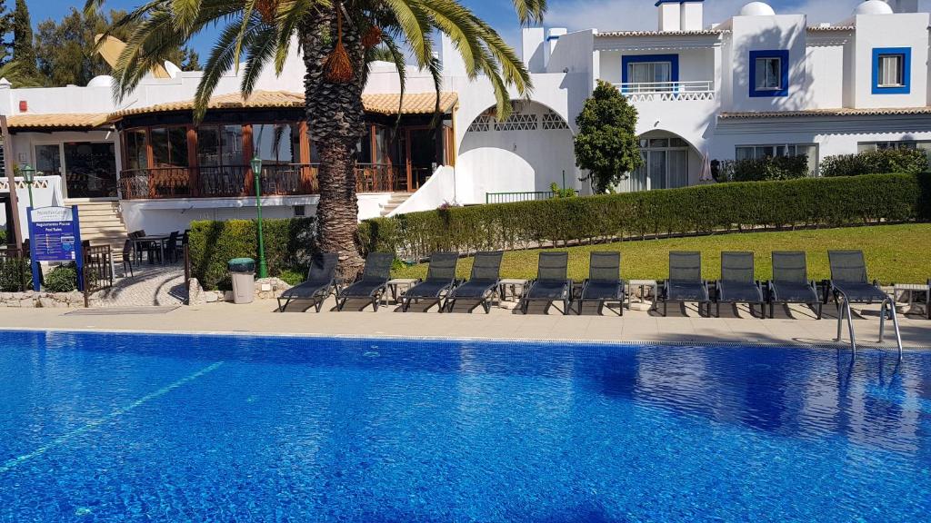 Pestana Palm Gardens Ocean & Golf Villas peldbaseins ar saulessargiem un palmu kokiem