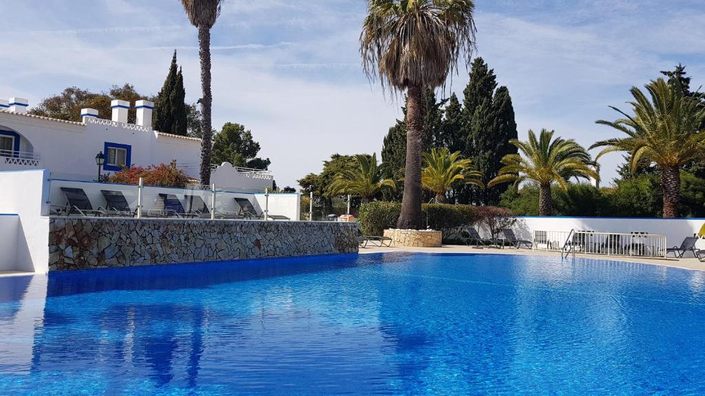 Pestana Palm Gardens Ocean & Golf Villas baseins ar palmām un saulessargiem