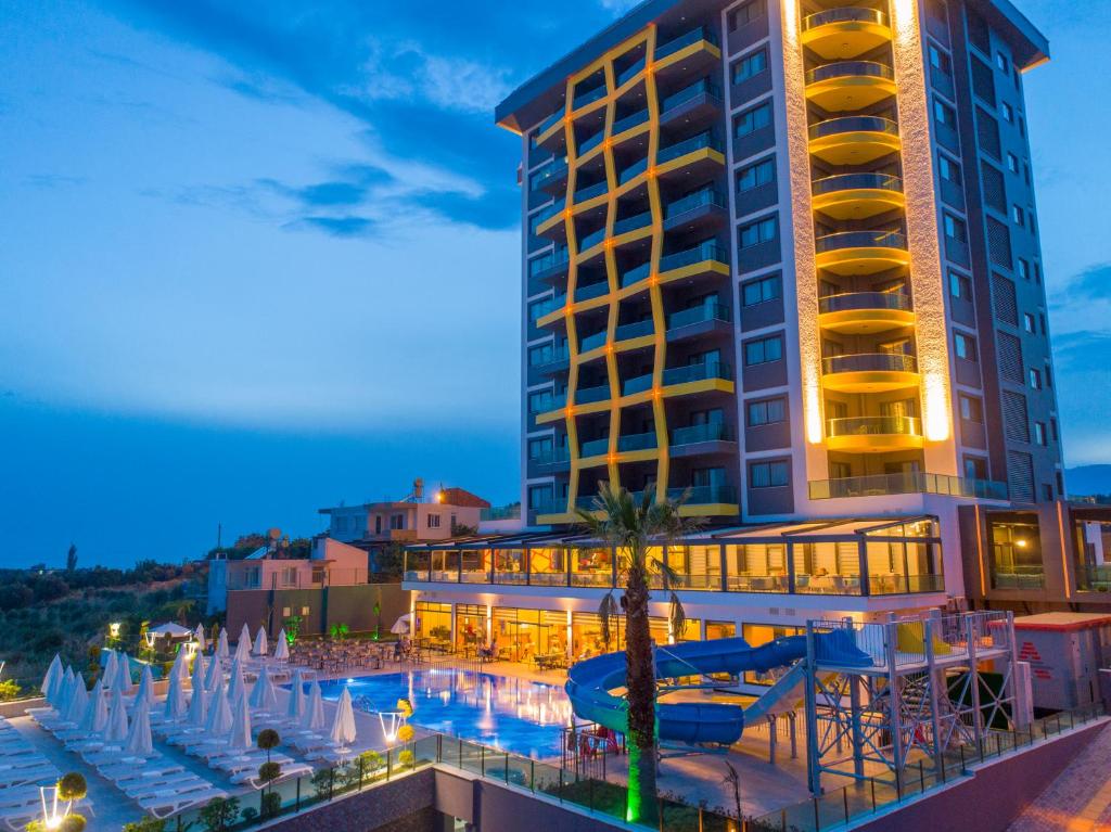 CAMPUS HILL HOTEL piekrastē ar baseinu un ūdens slidkalniņu vakarā.