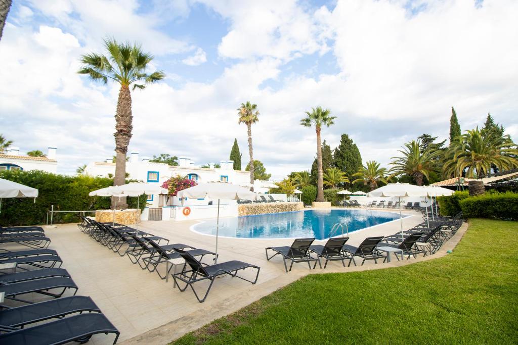 Pestana Palm Gardens Ocean & Golf Villas baseins ar palmām un sauļošanās krēsliem