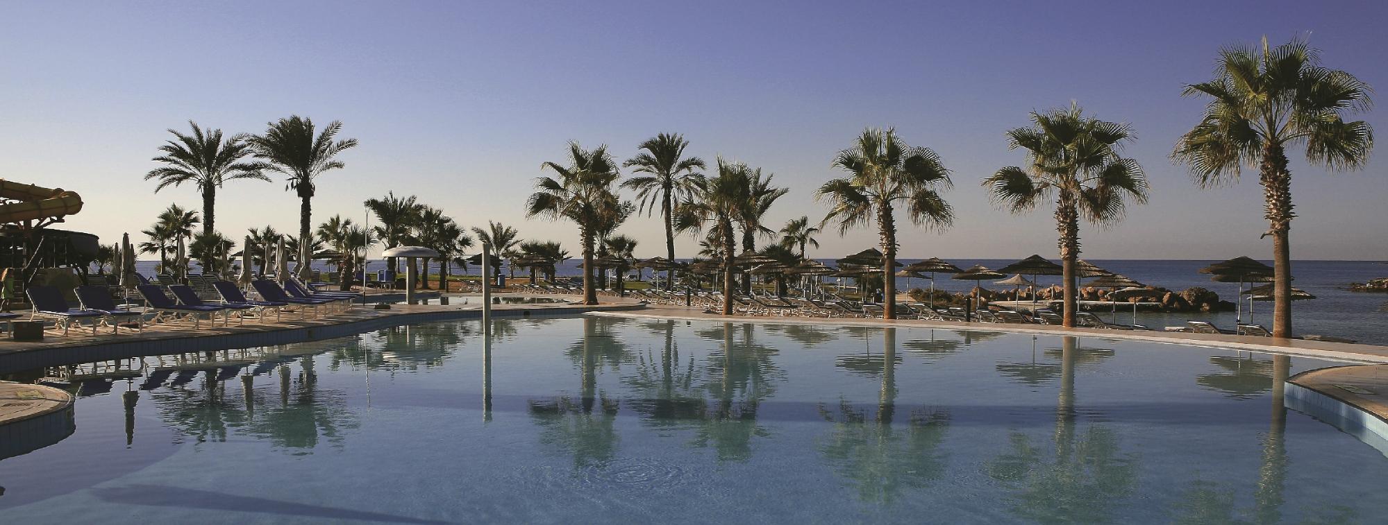 Adams Beach viesnīca ar baseinu un palmu koku skatu piekrastē.