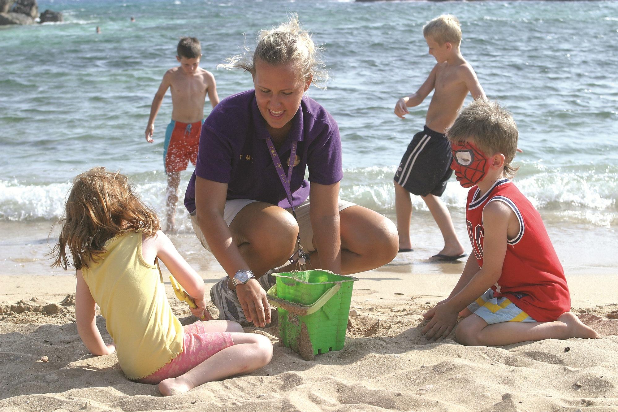 Bērni spēlējas pludmalē pie Adams Beach.