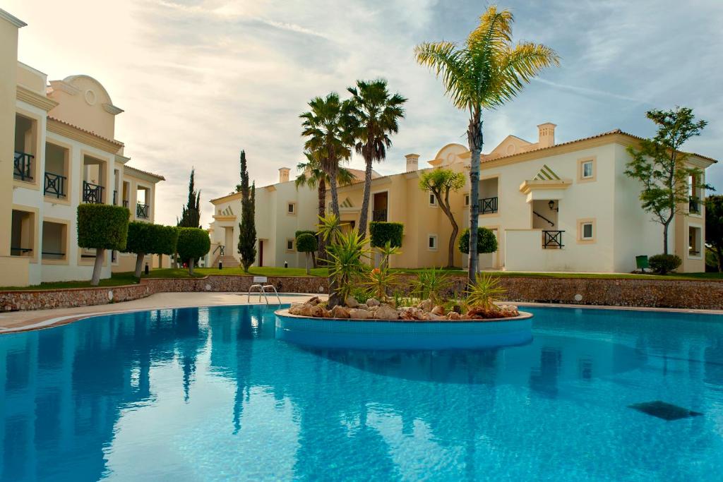 AP Adriana Beach Resort baseins ar palmu kokiem un viesnīcas numuriem