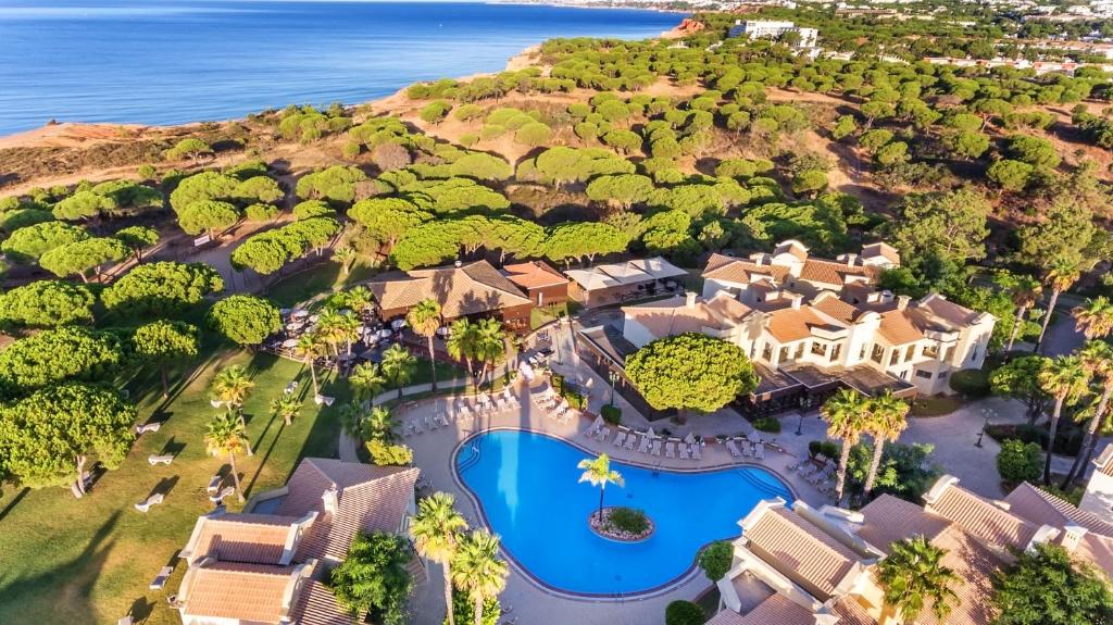 Skats uz AP Adriana Beach Resort piekrastē ar baseinu un zaļu ainavu.