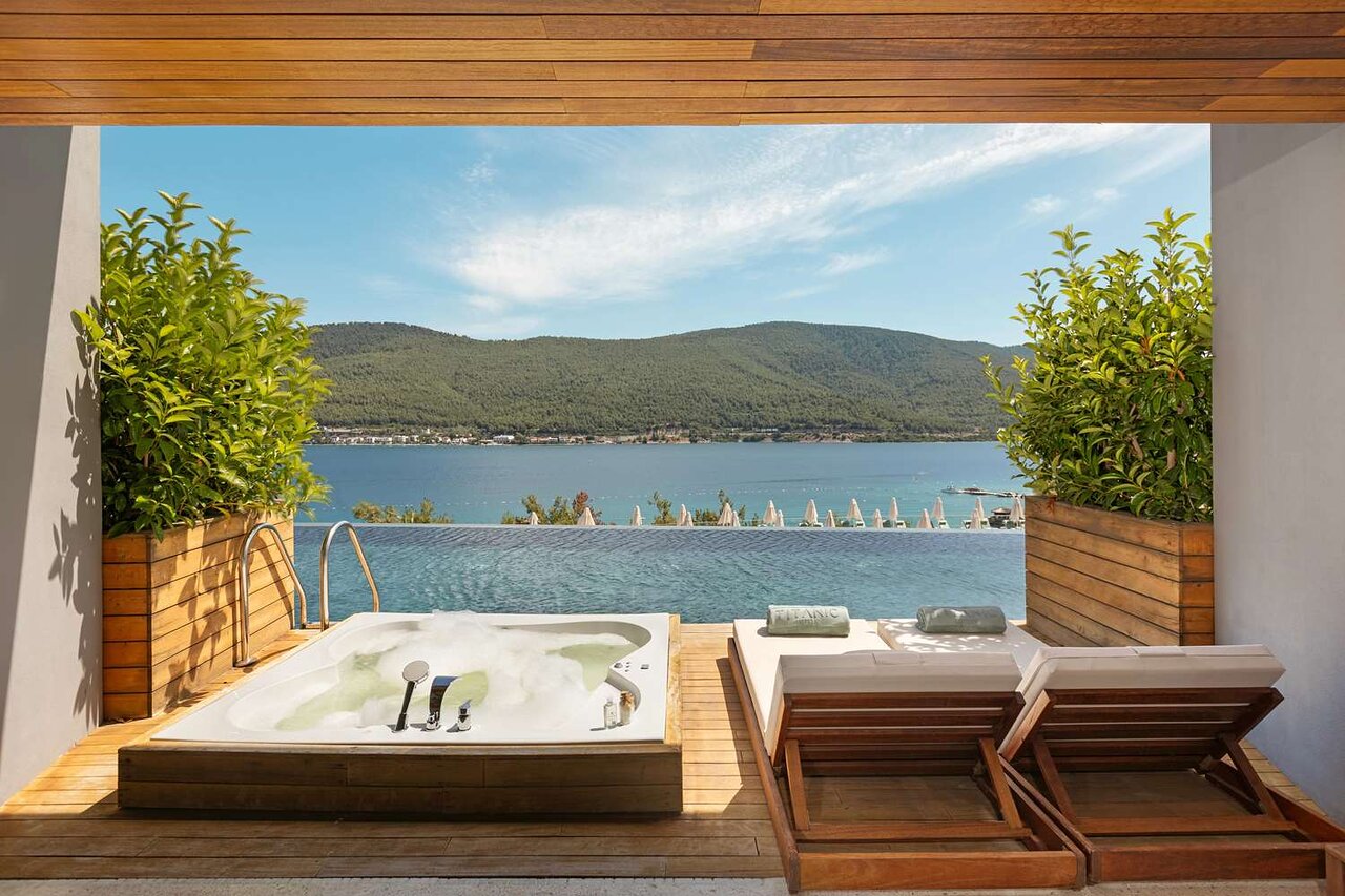 Greznas atpūtas zona ar džakuzi un saulessargiem, kas atrodas blakus gleznainam ezeram un kalniem. Ideāla vieta relaksācijai un atpūtai. panoramic view with beach and pools