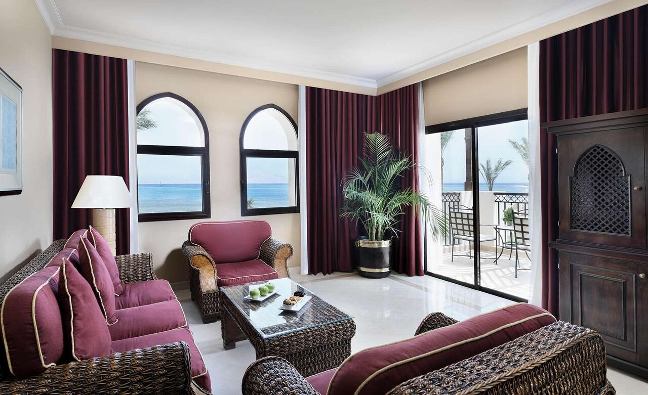 Mūsdienīgs viesnīcas numurs ar skatu uz jūru, kurā ir ērti mēbelēta atpūtas zona, palmas un eleganti aizkari. Ideāls atpūtai un relaksācijai. panoramic view with beach and pools