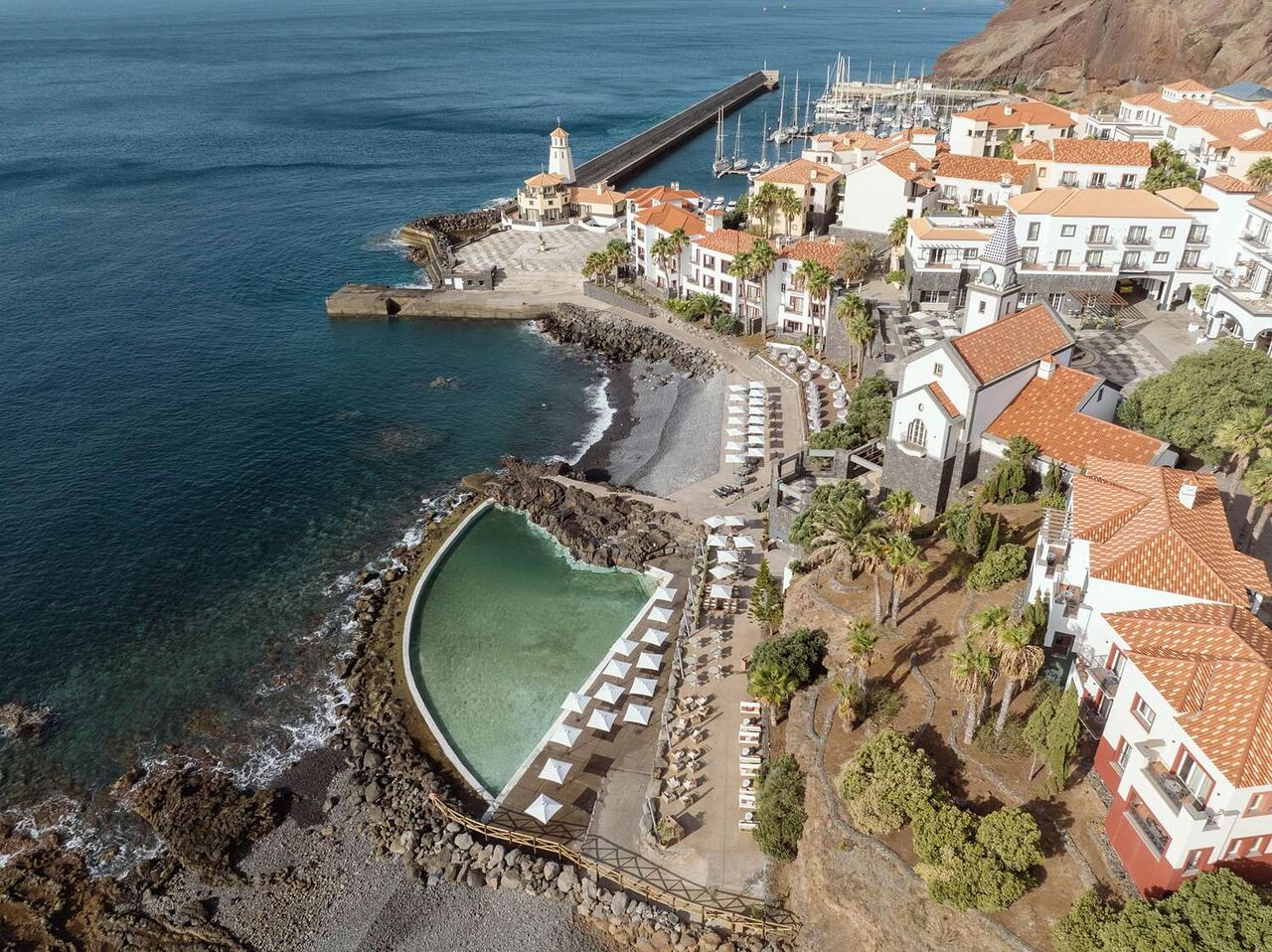 Skaista piekrastes ainava ar pludmali, baseinu un krasta mājām, kas atrodas blakus jūrai. Redzami jachtu piestātnes un kalnu reljefs fona. panoramic view with beach and pools