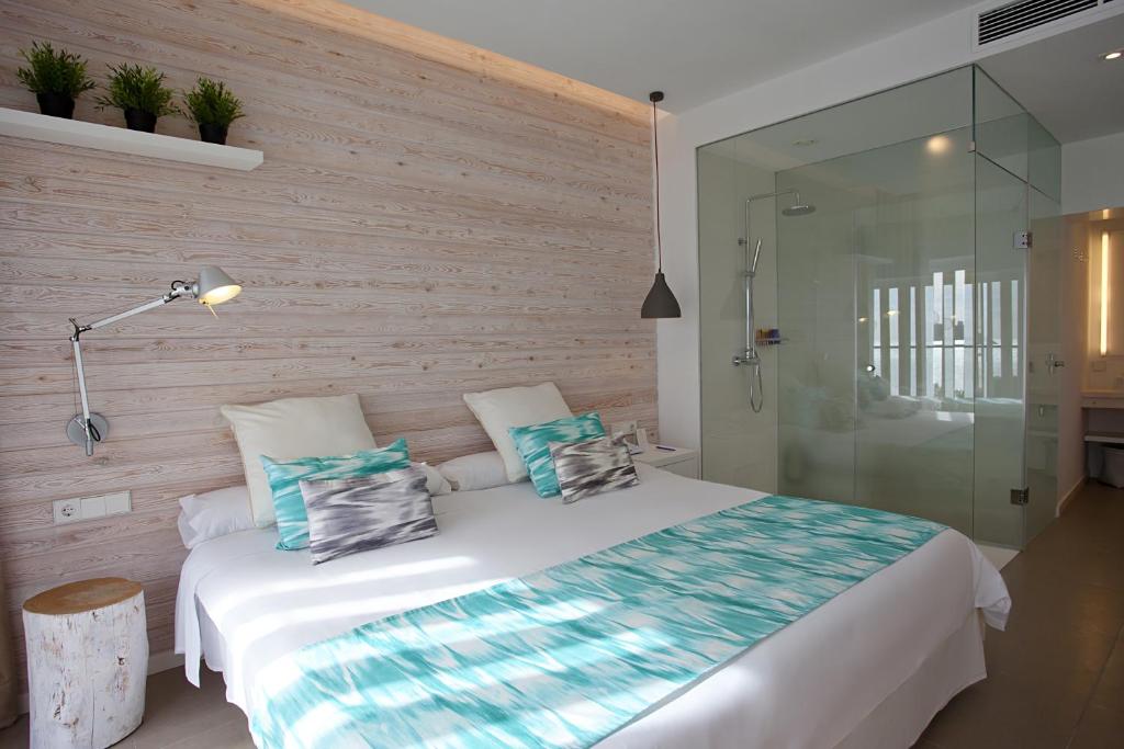 Mūsdienīga guļamistaba ar gaisīgiem toņiem, koka sienām un stikla dušu. Interjerā ir ērts divguļamais gultas veļas komplekts un dekoratīvie spilveni.