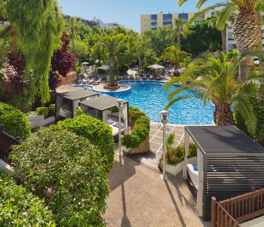 Vasaras brīvdienu oāze ar peldbaseinu un palmām, kas veido atpūtas vietu. Eleganti āra gultas un zaļumi pie baseina rada relaksējošu atmosfēru.