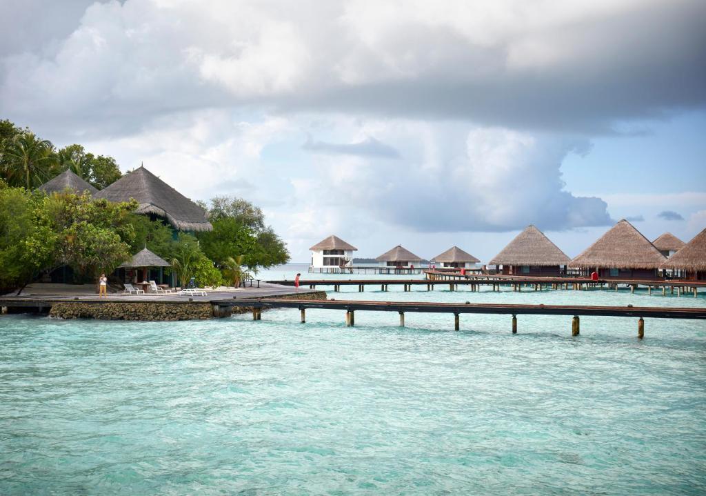 Tropu kūrorts pie ūdens ar koka tiltiem un tradicionālām jumta mājām. Mierīga atmosfēra un skaists skats uz zilo okeānu.