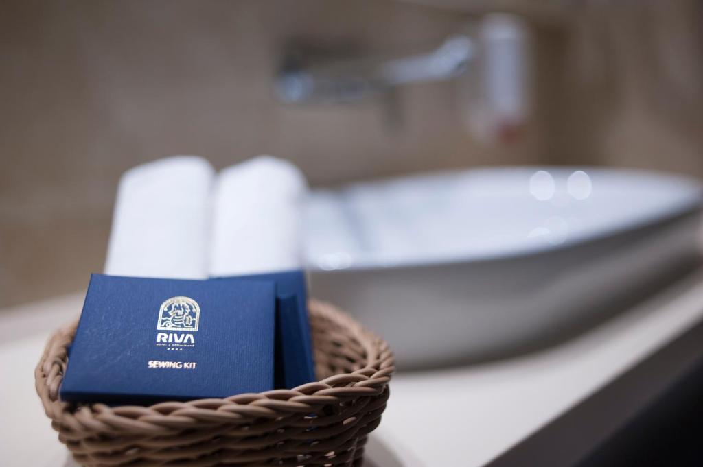 Sewing kit from RIVA displayed in a woven basket beside rolled towels and a modern sink in a stylish bathroom.
