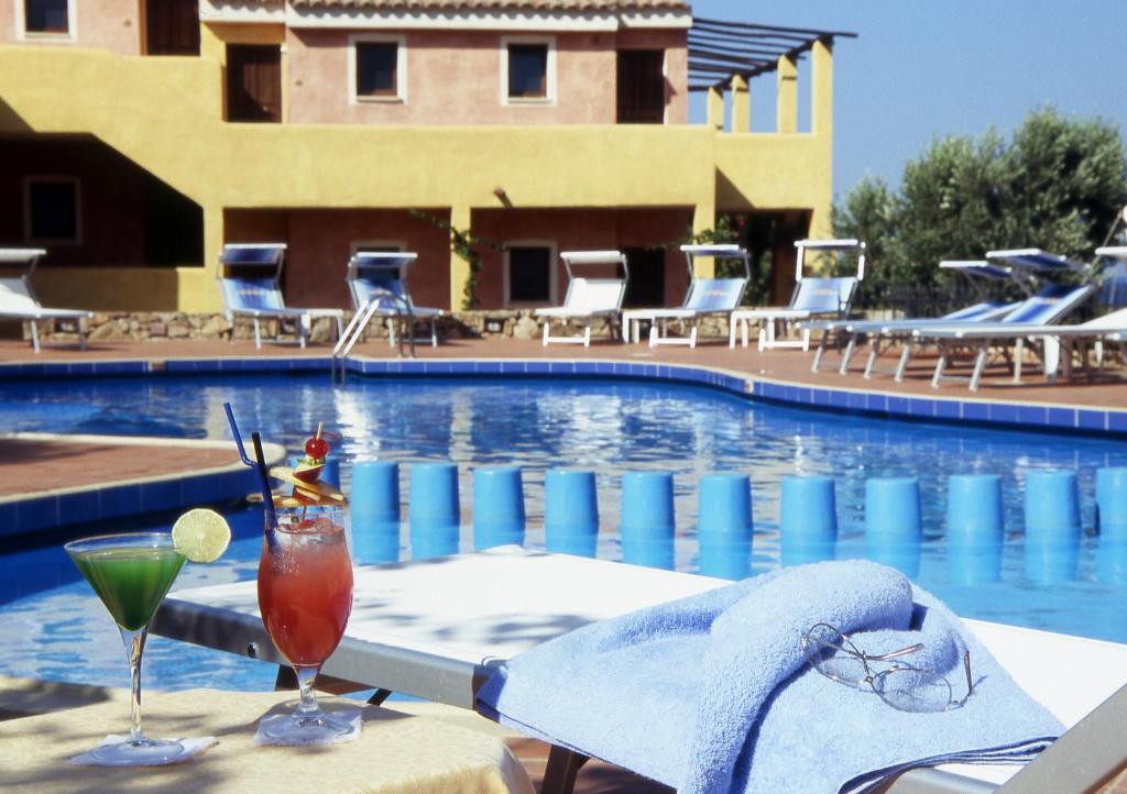Viesnīcas Stelle Marine baseins ar kokteiļiem un sauļošanās krēsliem.