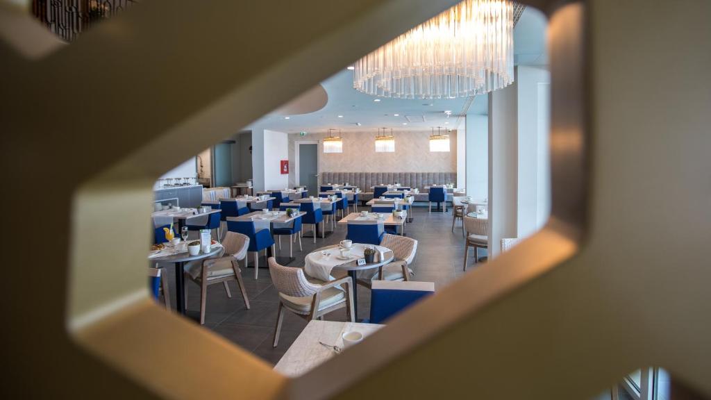 Mūsdienīgs restorāns ar elegantiem galdiem un zilu apdari, caur unikālu logu. Interjers ir gaišs un plašs, radot patīkamu atmosfēru.