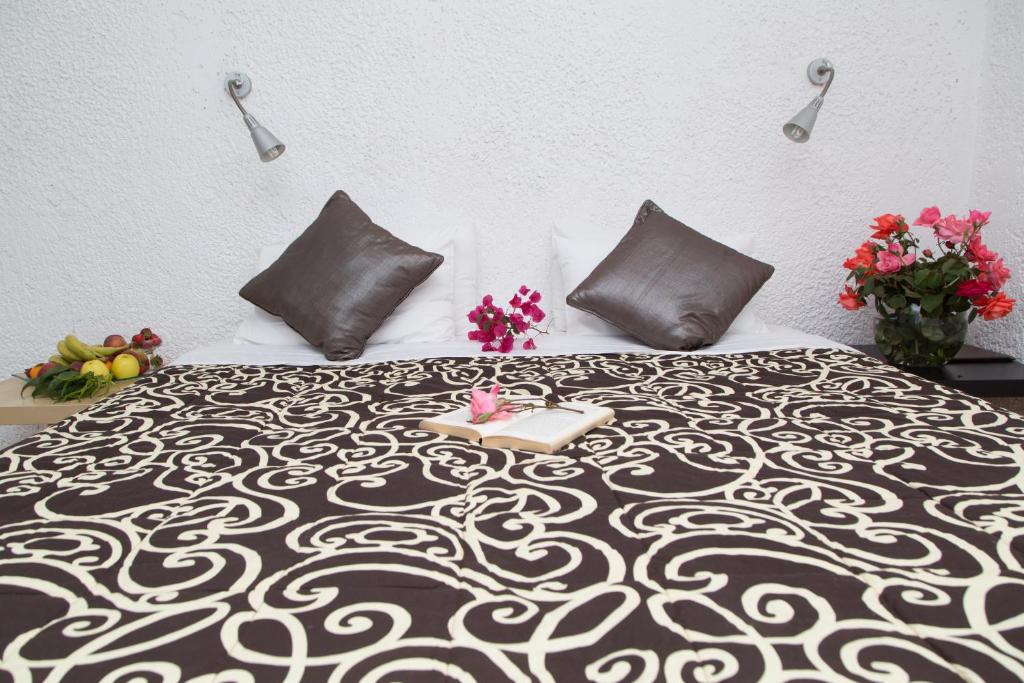 Mūsdienīgs guļamistabas interjers ar elegantu gultas pārklāju, spilveniem un ziediem, kas radījis mājīgu atmosfēru. Uz galda novietoti augļi, piešķirot telpai dzīvīgumu.