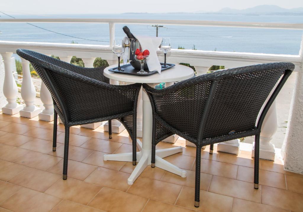 Balkona mēbeļu komplekts ar divām melnām krēslām un galdu, uz kura atrodas šampanieša pudele un glāzes, ar skatu uz jūru.