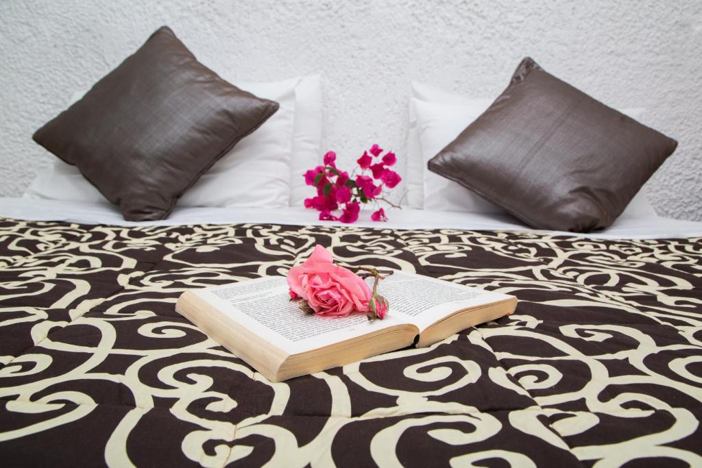 Gultas kompozīcija ar grāmatu, rozēm un spilveniem, kas rada mierīgu un viesmīlīgu atmosfēru. Ideāli piemērota relaksācijai un lasīšanai.