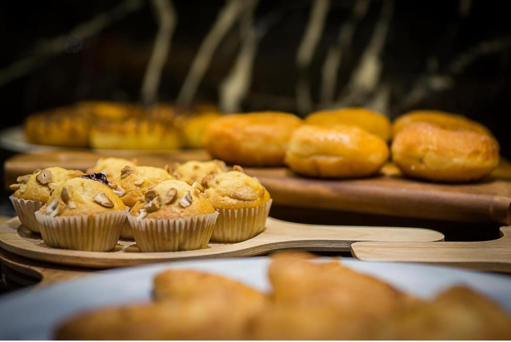 Svaigi izcepti kūciņas un maizes izstrādājumi uz koka paliktņa, piedāvājot gardu desertu izvēli. Ideāls attēls saldumu mīļotājiem.