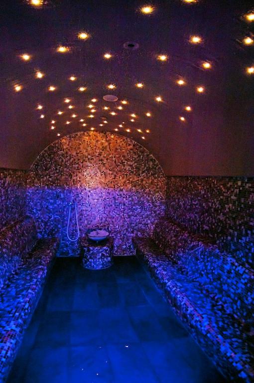 Relaksējoša tvaika pirts ar mozaīkas apdari un zvaigžņu gaismiņām. Telpa ir izgaismota ar zilu gaismu, radot mierīgu atmosfēru.