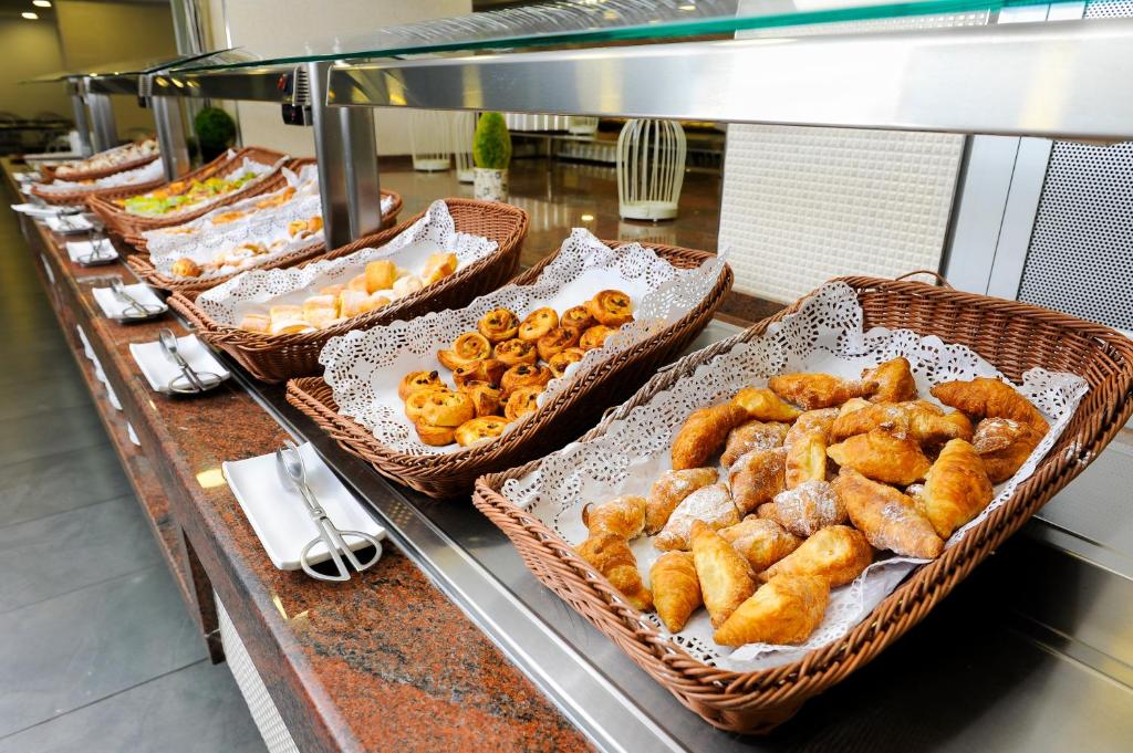 Piknika galda ar dažādiem kārumiem, tostarp smalkmaizītēm un konditorejas izstrādājumiem, kas pasniegti grozos ar dekoratīvām papīra salvetēm.