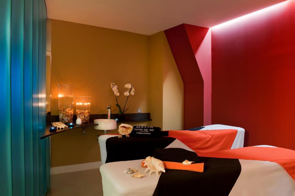 Mūsdienīgs spa telpas interjers ar relaksējošu atmosfēru, dekorēts ar siltām krāsām un elegantiem aksesuāriem. Uz masāžas galdiem ir novietotas dvieļi un dekoratīvi elementi, radot mierīgu vidi.