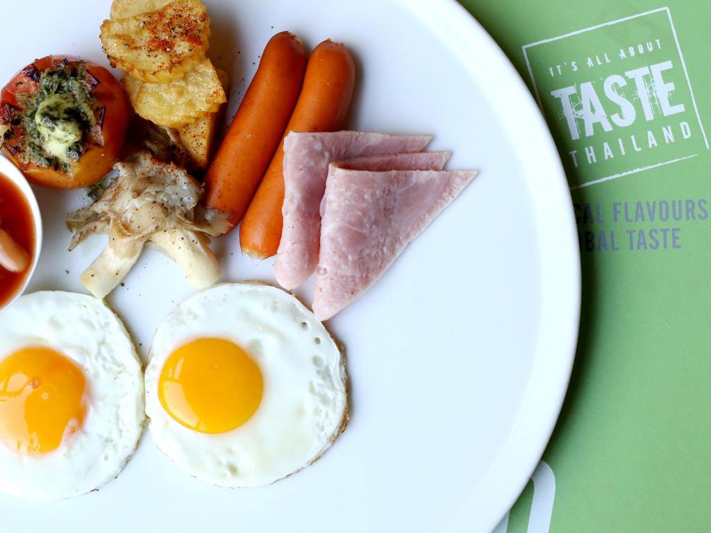 Tradicionāls brokastu šķīvis ar ceptām olām, desiņām, šķiņķi, ceptiem kartupeļiem un tomātu ar garšvielām. Fons ar 